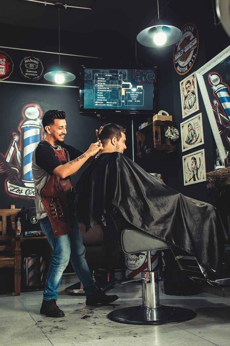 A barber skillfully cutting a man's hair in a trendy, well-decorated barbershop.