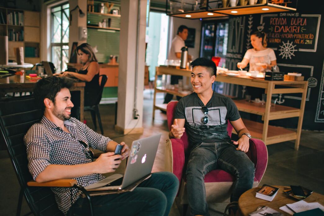 Two men enjoying a relaxed conversation with laptops in a cozy Brazilian café.