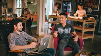 Two men enjoying a relaxed conversation with laptops in a cozy Brazilian café.