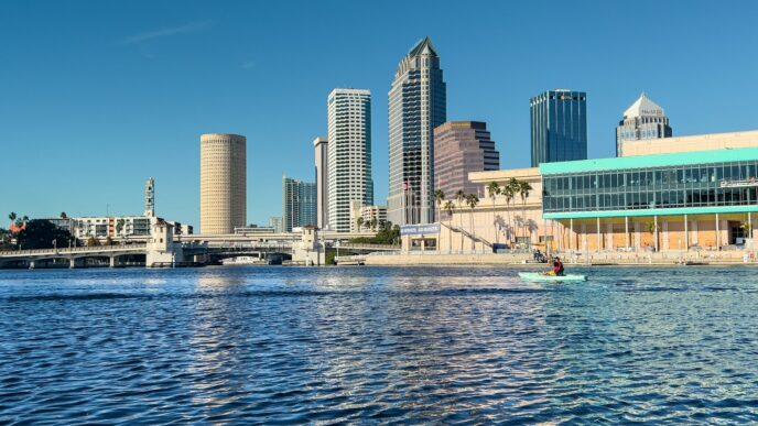 a man in a boat on a river in front of a city