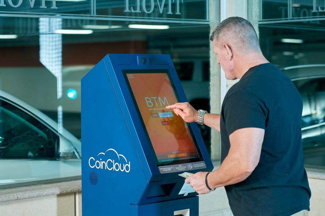 Man interacts with a CoinCloud Bitcoin ATM indoors, facilitating cryptocurrency exchange.