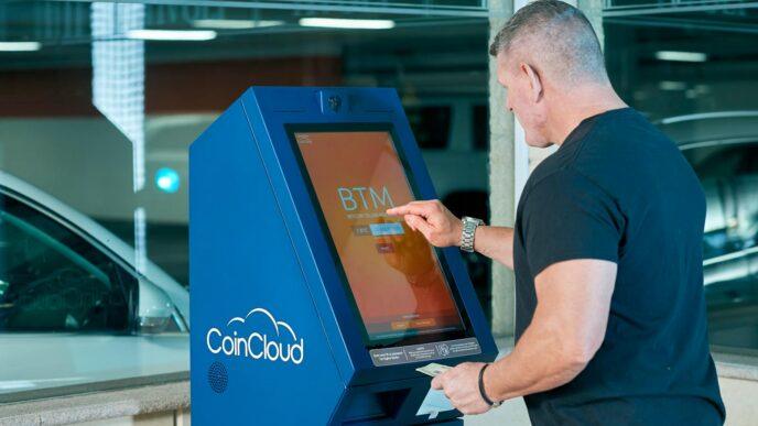 Man interacts with a CoinCloud Bitcoin ATM indoors, facilitating cryptocurrency exchange.