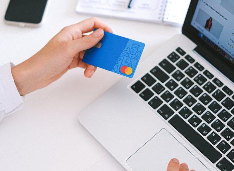 Person making an online purchase with a credit card on a laptop, showcasing modern ecommerce technology.