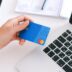 Person making an online purchase with a credit card on a laptop, showcasing modern ecommerce technology.
