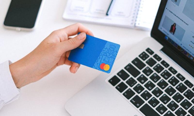 Person making an online purchase with a credit card on a laptop, showcasing modern ecommerce technology.