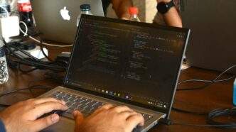 a man using a laptop computer on a wooden table