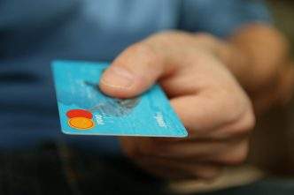 27 Best Stripe Alternatives To Accept Payments In Your Business 9 A close-up shot of a hand offering a blue debit card for payment.