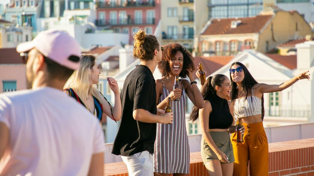 A lively group of friends enjoying a rooftop party in Portugal under a bright summer sun.