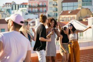 A lively group of friends enjoying a rooftop party in Portugal under a bright summer sun.